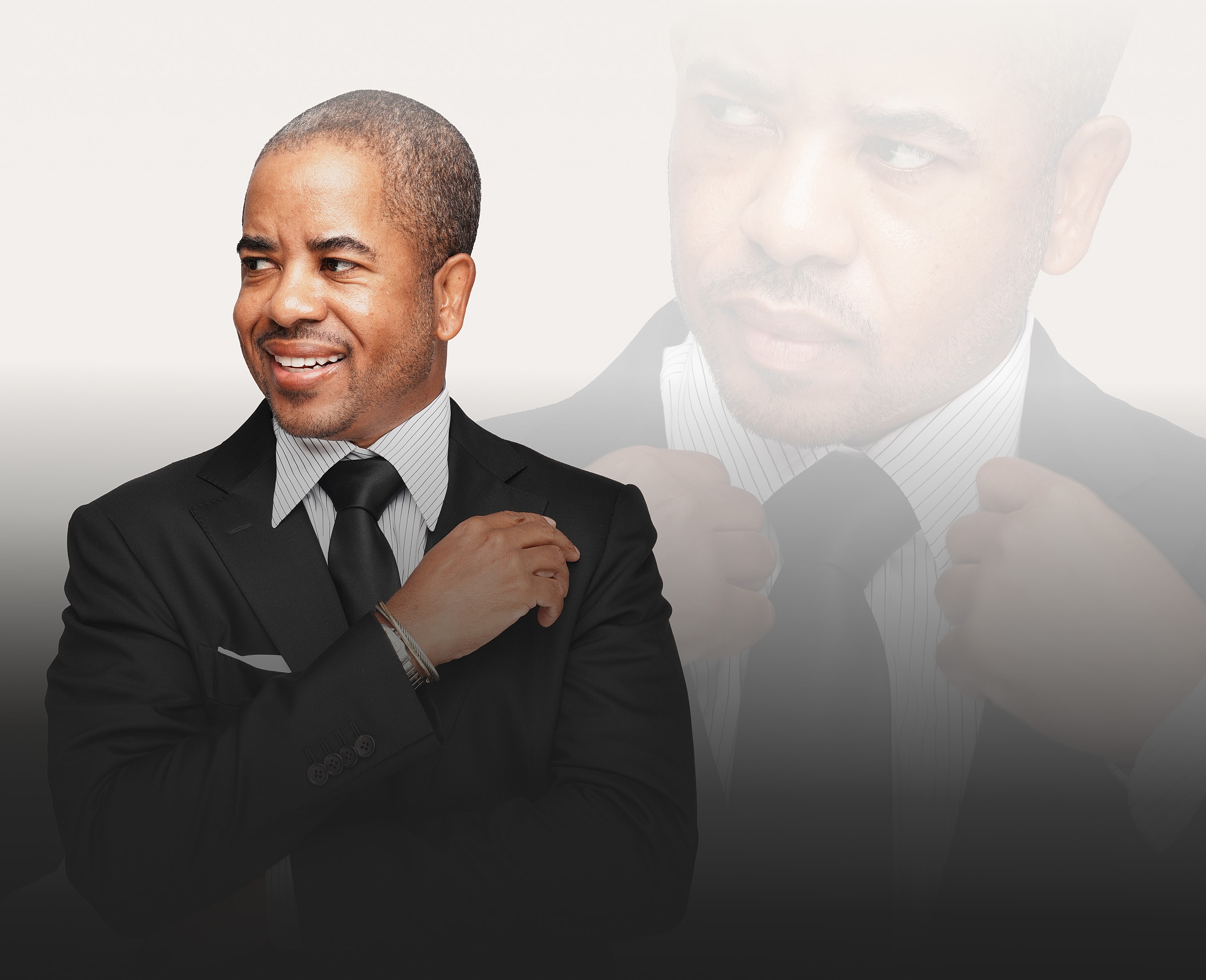 Smiling man in a black suit, confident pose.