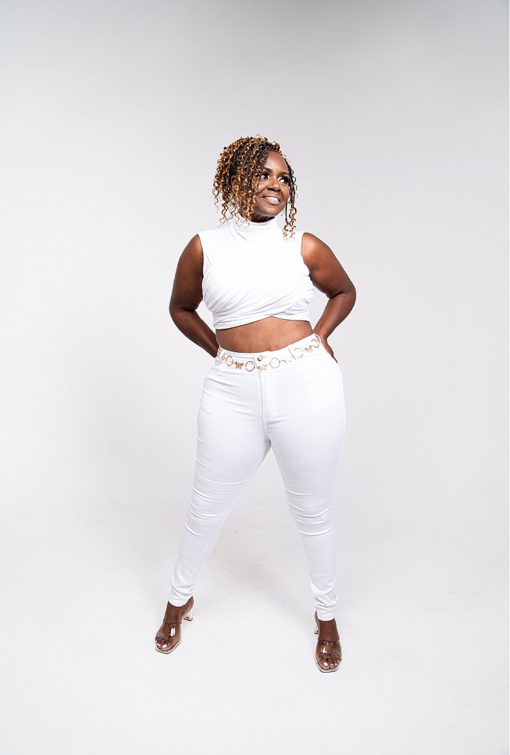 Model wearing stylish white outfit, smiling confidently.